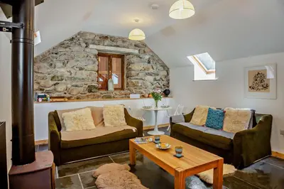 a living room with two couches and a stone wall at 1 Bed in Brithdir oc-w30045 in Rhydymain