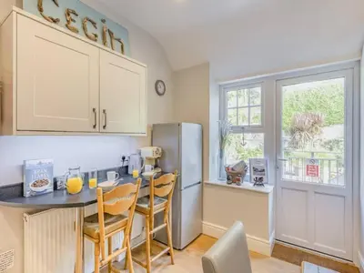 a kitchen with a table and chairs and a refrigerator at Pencartref- Luxurious Seaside Apartment Aberdovey in Aberdyfi