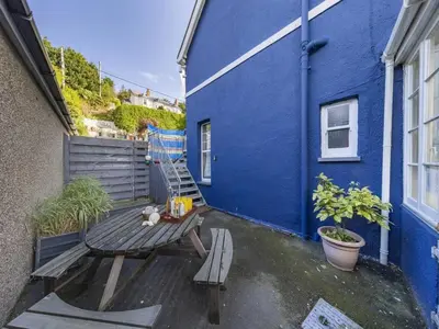 a blue building with a bench and a blue wall at Pencartref- Luxurious Seaside Apartment Aberdovey in Aberdyfi