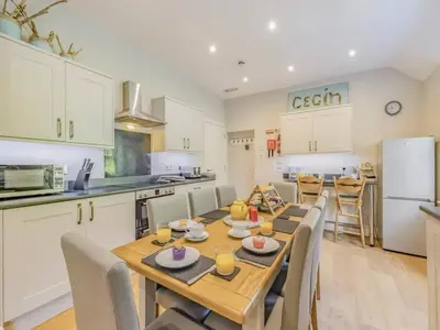 a kitchen and dining room with a wooden table and chairs at Pencartref- Luxurious Seaside Apartment Aberdovey in Aberdyfi