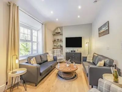 a living room with couches and a tv at Pencartref- Luxurious Seaside Apartment Aberdovey in Aberdyfi