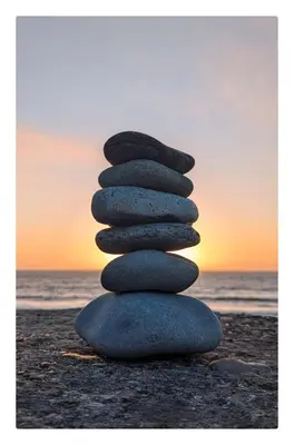 a stack of three rocks sitting on a beach at Y Mor Cosy Apartment in Tywyn