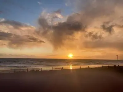 a sunset on the beach with the sun setting at Y Mor Cosy Apartment in Tywyn