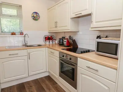 a kitchen with white cabinets and a sink and a microwave at Trem-Yr-Afon in Lampeter