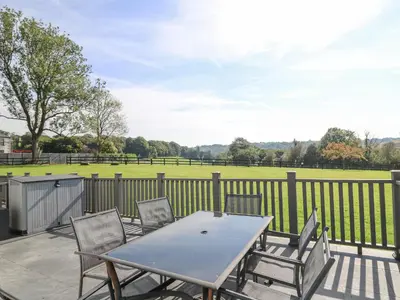 a table and chairs on a patio with a field at Trem-Yr-Afon in Lampeter