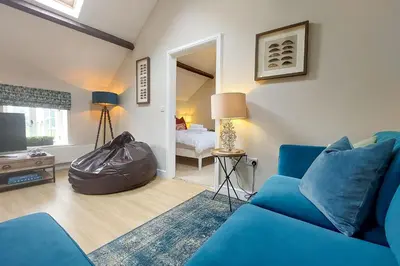 a living room with a blue couch and a bedroom at The Annexe in Chirbury