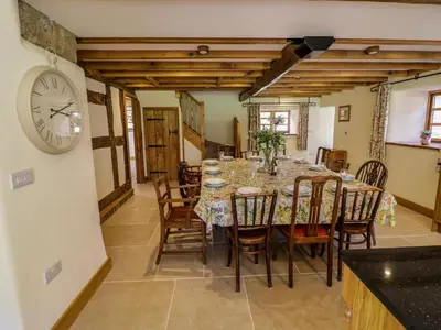a dining room with a table and a clock on the wall at Grove Farm in Church Stretton