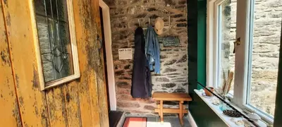 a door to a room with a shirt hanging on a wall at Cwt Mochyn Aberaeron in Cross Inn