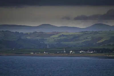 a large body of water with mountains in the background at Cwt Mochyn Aberaeron in Cross Inn