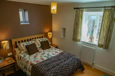 a bedroom with a bed and a window at Cwt Mochyn Aberaeron in Cross Inn