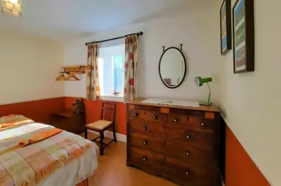a bedroom with a bed and a dresser with a mirror at Cwt Mochyn Aberaeron in Cross Inn