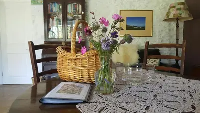 a table with a vase of flowers and a basket at Hen Ffermdy Aberaeron in Cross Inn