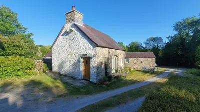 an old stone building with a door on a road at Hen Ffermdy Aberaeron in Cross Inn