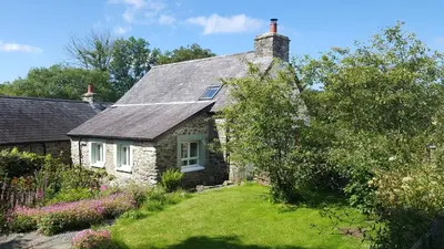 a stone house with a garden in front of it at Hen Ffermdy Aberaeron in Cross Inn