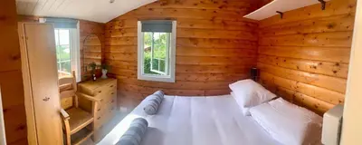 a bedroom with a white bed in a wooden room at Caban Marjie in Trawsfynydd