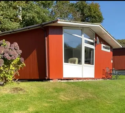a red and white shed with a large window at Chalet 7 Erw Porthor in Tywyn