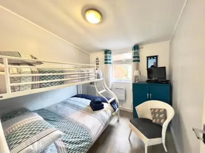 a bedroom with two bunk beds and a chair at Chalet 7 Erw Porthor in Tywyn