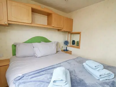 a bedroom with a bed with towels on it at D12 Treetops in Aberystwyth