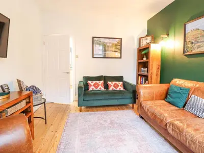 a living room with a couch and a chair at Tŷ Kinik in Llangollen