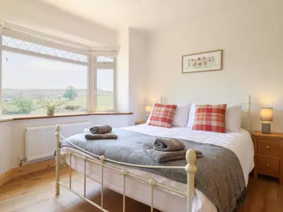 a bedroom with a bed with pillows and a window at Bryn Bras in Corwen