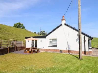 a white house with a picnic table in a yard at Bryn Bras in Corwen