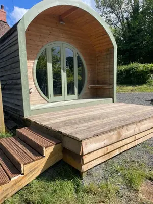a tiny house with a circular window and a wooden deck at Damson Lodge in Hereford