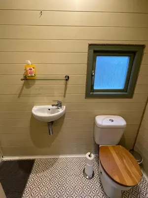 a bathroom with a toilet and a sink and a window at Damson Lodge in Hereford