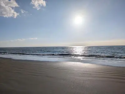 a beach with the sun rising over the ocean at Cartref Guesthouse - Room 1 Ensuite in Aberdyfi