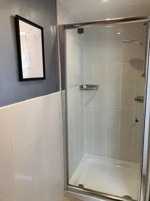 a shower with a glass door in a bathroom at Cartref Guesthouse - Room 1 Ensuite in Aberdyfi