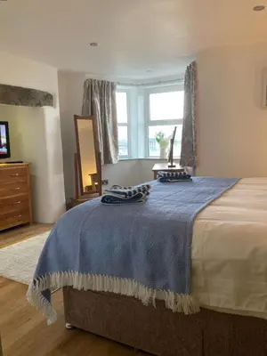 a bedroom with a large bed with a blue blanket at Wynnstay Apartment, Harbour and Mountain Views in Barmouth