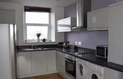 a kitchen with white cabinets and a washer at Wynnstay Apartment, Harbour and Mountain Views in Barmouth