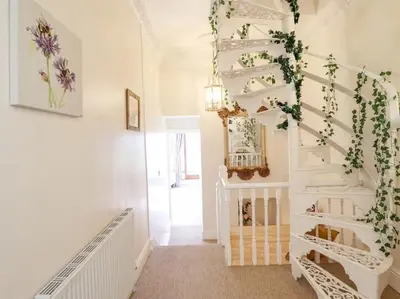 a white hallway with a spiral staircase with flowers at Bryn Glasfor in Barmouth