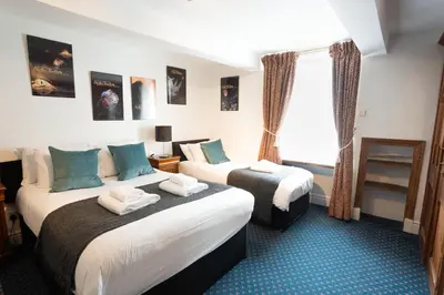 a hotel room with two beds and a window at Without A Paddle Hotel in Llangollen