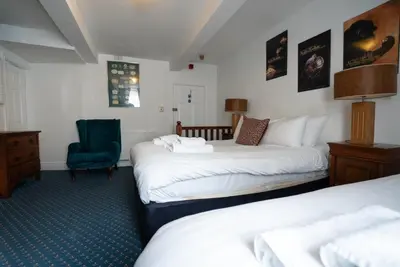 a hotel room with two beds and a blue chair at Without A Paddle Hotel in Llangollen