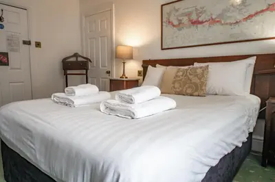 a bedroom with a white bed with towels on it at Without A Paddle Hotel in Llangollen