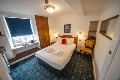 a bedroom with a bed and a chair and a window at Without A Paddle Hotel in Llangollen