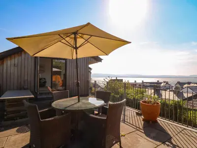 a table and chairs with an umbrella on a balcony at 1 Gibraltar Terrace in Aberdyfi