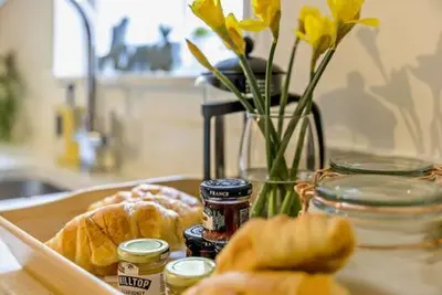 a table with a tray of bread and a vase with flowers at Beautiful Town Centre Apartment 110 Square Metre With Parking WEEKLY and MONTHLY Reduced Rates in Shrewsbury