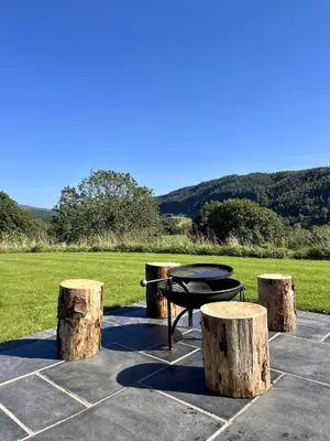 a patio with a table and three tree stumps at Y Fedwen in Llanwddyn