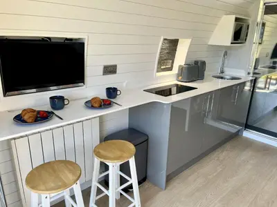 a kitchen with a counter with two stools and a sink at Y Fedwen in Llanwddyn