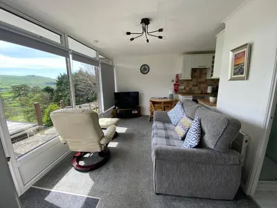 a living room with a couch and a chair and a window at Chalet 8 The Woodlands in Tywyn