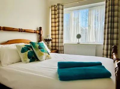 a white bed with a blue pillow on it at Snowdonia coastal getaway ideal for groups up to 6 in Llwyngwril
