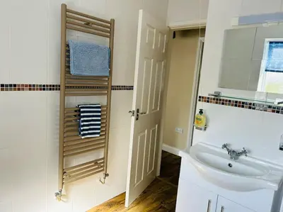 a white bathroom with a sink and a mirror at Snowdonia coastal getaway ideal for groups up to 6 in Llwyngwril