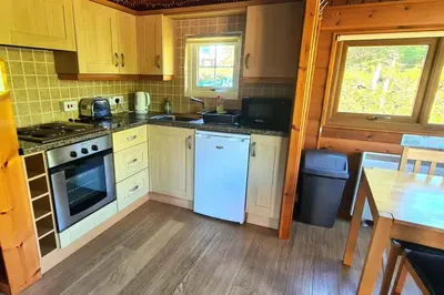 a kitchen with white appliances and a wooden floor at Cosy log cabin in Snowdonia 19 in Trawsfynydd