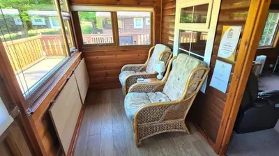 a room with two wicker chairs in a train car at Cosy log cabin in Snowdonia 19 in Trawsfynydd