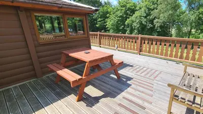 a picnic table and a bench on a deck at Cosy log cabin in Snowdonia 19 in Trawsfynydd