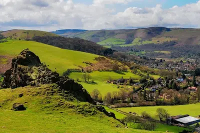 a green hillside with a village in the distance at Ludlow Mews Town House with Free parking in Ludlow