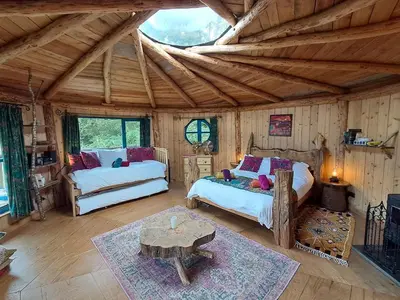 a bedroom with two beds and a table in a room at Magical Offgrid Roundhouse in Eryri in Machynlleth