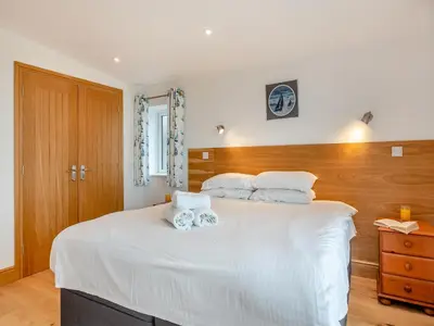 a bedroom with a white bed with two stuffed animals on it at Bodwennol in Aberdyfi