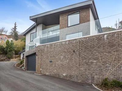 a building with a brick wall and a driveway at Bodwennol in Aberdyfi